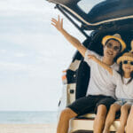 What Are The Most Common Names In The U.K.? Family Day. Father, Mother and daughter enjoying road trip sitting on family back car raise hand up, Happy people having fun in summer vacation on beach, Family traveling in holiday at sea beach