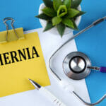 Hernia – Word On A Yellow Notebook On A Blue Background With A S