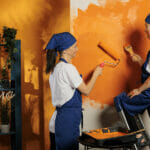 Mom And Girl Painting Room Walls With Orange Color Paint, Using