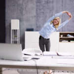 Arms Stretch Exercise Standing Near Desk In Office