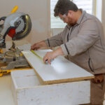 An Employee Uses Circular Saw To Cut Melamine Board For Shelves