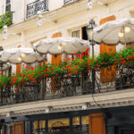 Elevate Your Brand Outdoors: The Business Benefits of Custom Cafe Umbrellas Paris cafe with a balcony patio and umbrellas