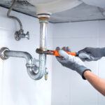 Technician Plumber Using A Wrench To Repair A Water Pipe Under T