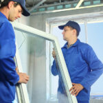 Two workers in blue work clothes set a new window in the window