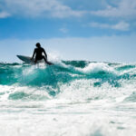 Customizable Surf Coaching: Pacific Surf School’s Personalized Approach to Developing Individual Skills Surfing in nice weather with great waves and blue skyline.