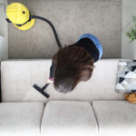 Woman In Apartment Cleans Sofa With Vacuum Cleaner. Wet Cleaning