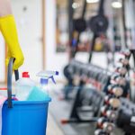 How Cleanliness Affects Your Gym’s Reputation: The Role of Cleaning Services Gym Cleaning Concept. Cleaning Lady Stands With A Bucket And Cle