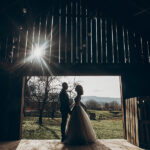 Stylish Bride And Groom Hugging In Sun Light On Background Of Wo