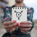closeup of a young caucasian woman outdoors showing a notepad in